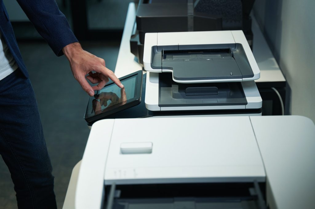 Person in office using printer and pressing on its screen